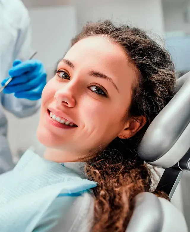 Una mujer sonríe mientras está sentada en una silla dental.