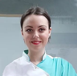Una mujer con cabello rojo viste un uniforme azul y sonríe.