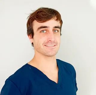 Un hombre con una blusa azul sonríe para la cámara.