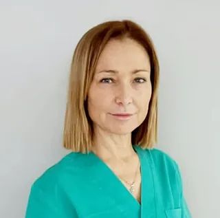 Una mujer con un uniforme verde está parada frente a una pared blanca.