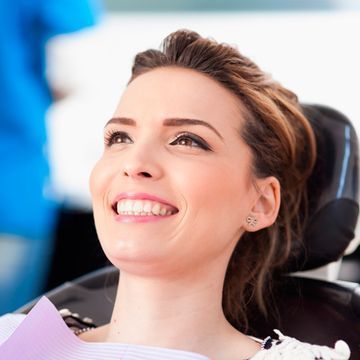 Una mujer sonríe mientras está sentada en una silla dental.
