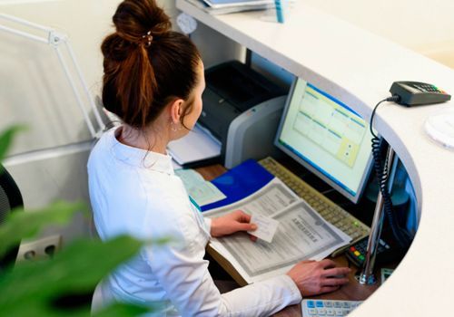 Una mujer está sentada en un escritorio frente a una computadora.