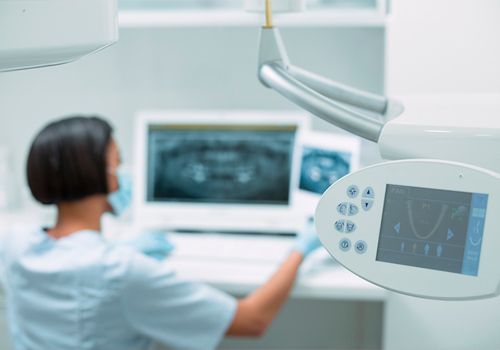 Una dentista está trabajando en una computadora en un consultorio dental.