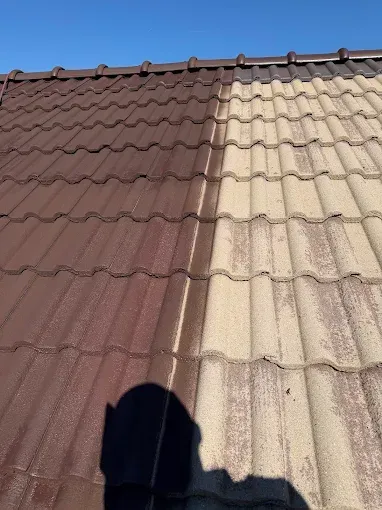 Toiture en tuiles bicolores baignée de soleil, avec l'ombre d'une personne à sa base.
