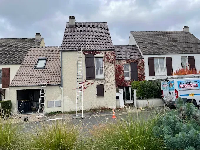 Maisons de banlieue avec des travaux de réparation de toiture, une échelle et une camionnette d'entrepreneur garée devant.