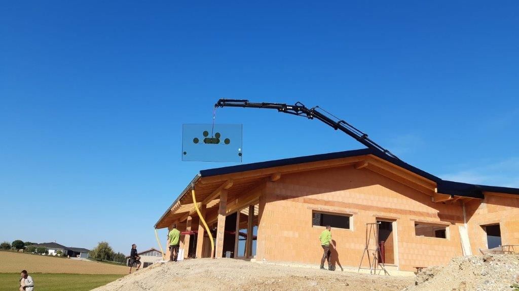 Von einem Baukran hängt eine Fensterscheibe zum Einsetzen
