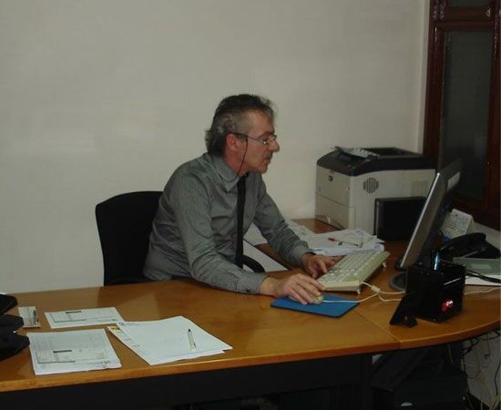 Homem sentado à mesa digitando em um computador em um escritório.