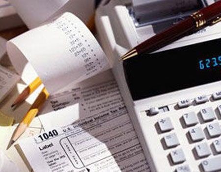 Calculadora ao lado de recibos e um caderno com caneta sobre a mesa
