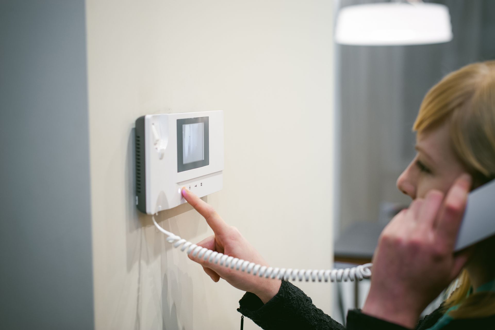 Femme ouvrant la porte de sa maison à l'aide de l'interphone