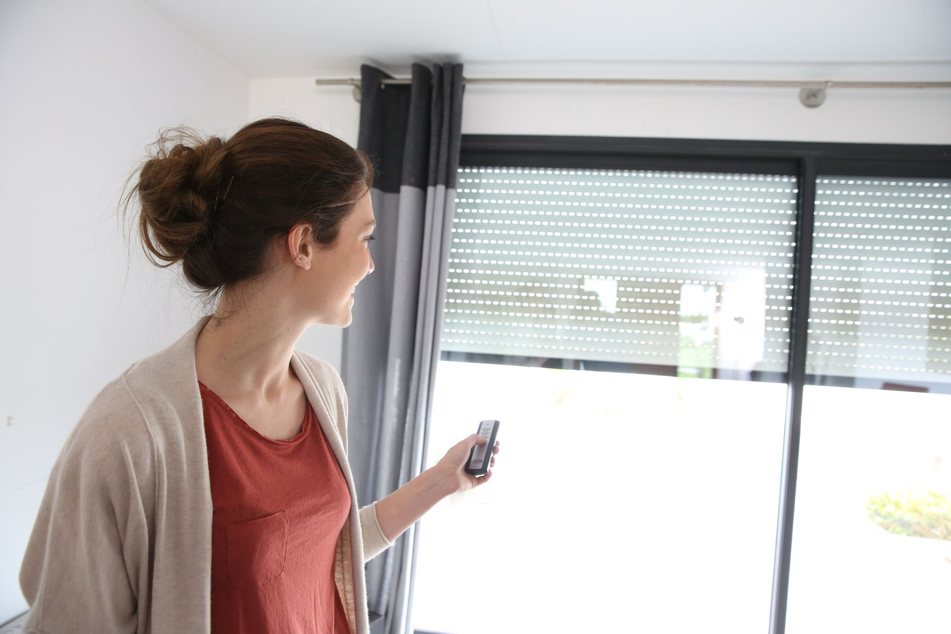 Une femme en train de fermer des volets roulants via une télécommande