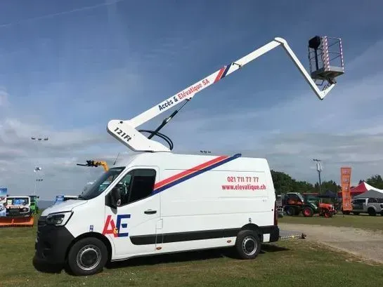 Un ouvrier lave les vitres d'un immeuble moderne dans un ascenseur. Ciel bleu. Chariot élévateur blanc.