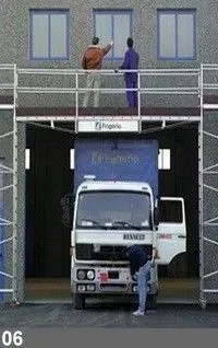 Des ouvriers sur une plateforme au-dessus d'un camion inspecté. Couleurs : gris, bleu et blanc.