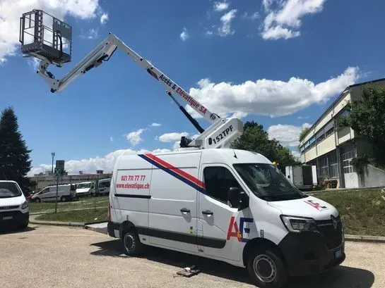 Une camionnette blanche avec nacelle élévatrice déployée devant un bâtiment par une journée ensoleillée.