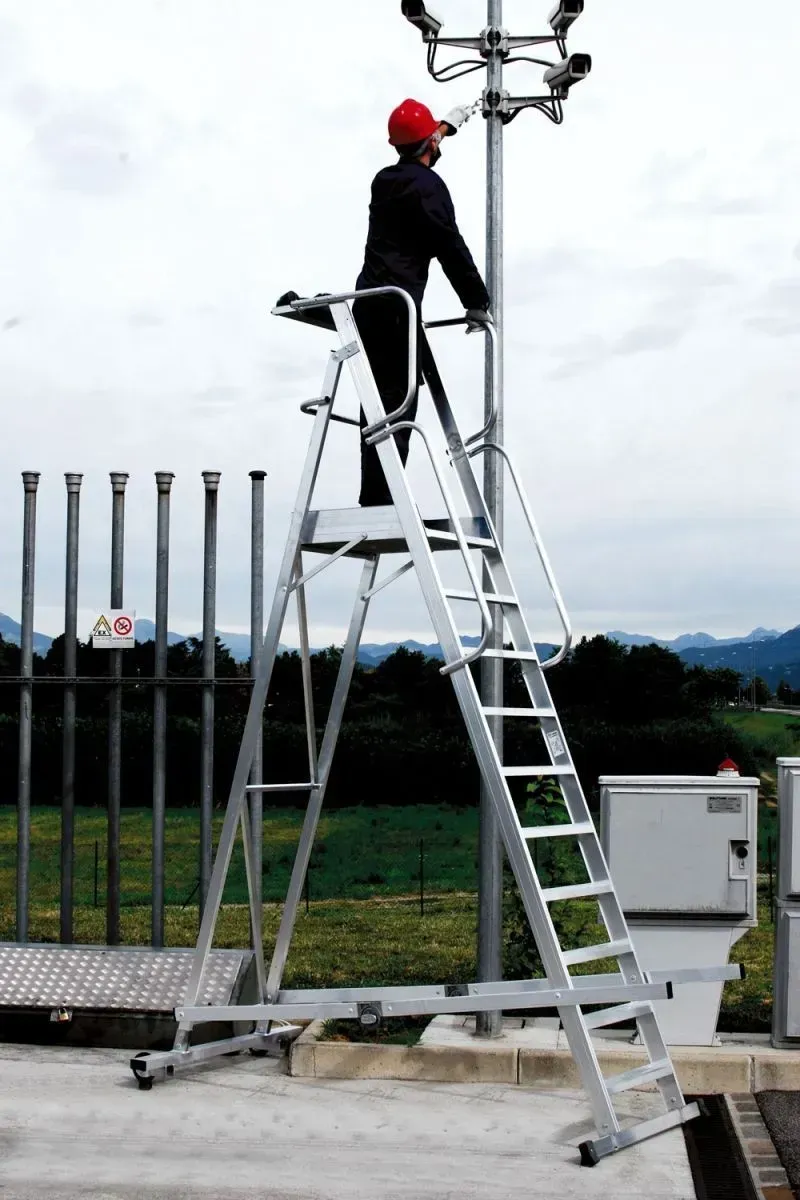 Une personne portant un chapeau rouge sur une grande échelle, travaillant sur des caméras de surveillance à l'extérieur.