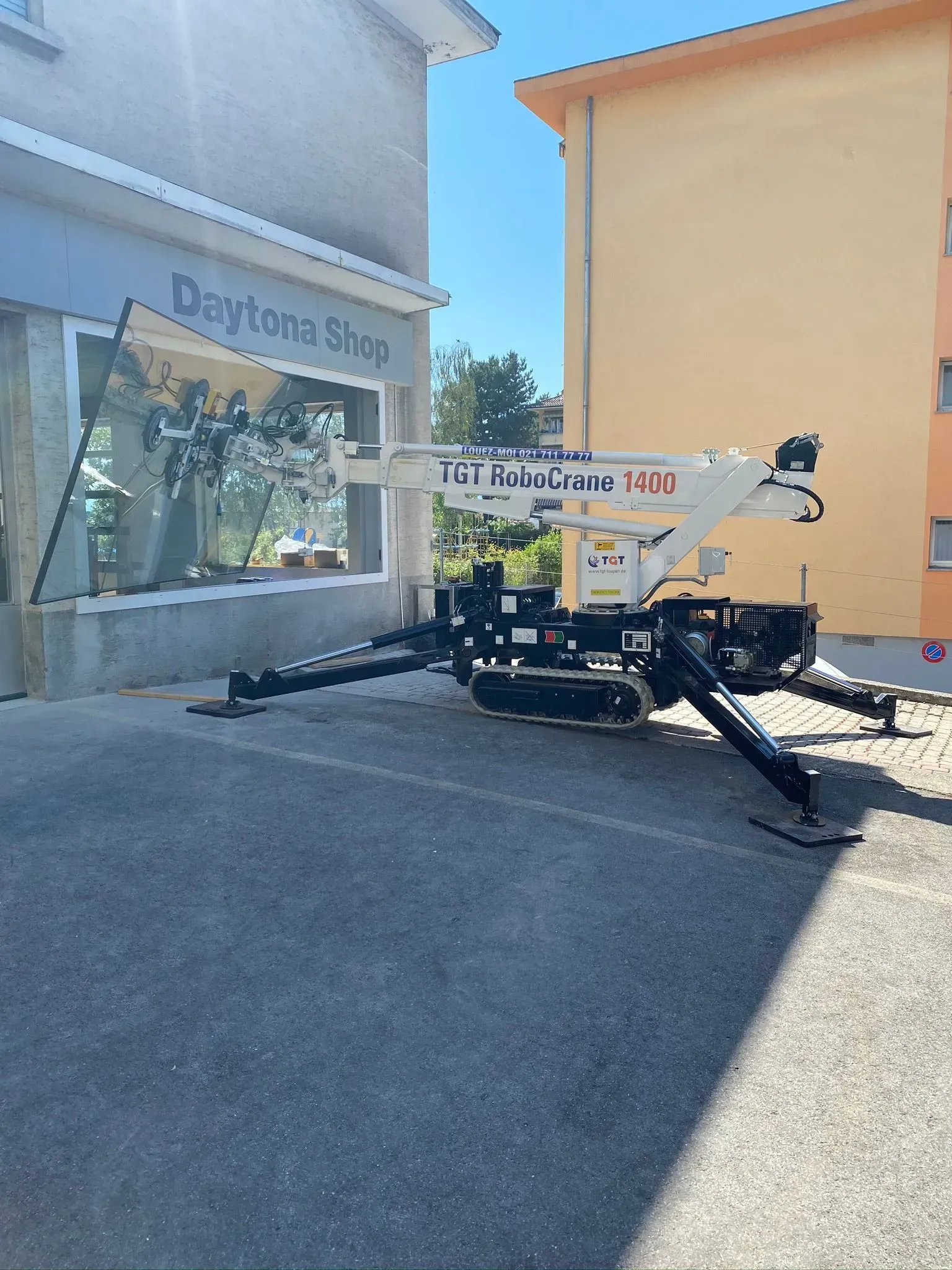 Une grue blanche et noire devant un bâtiment « Daytona Shop » par une journée ensoleillée.