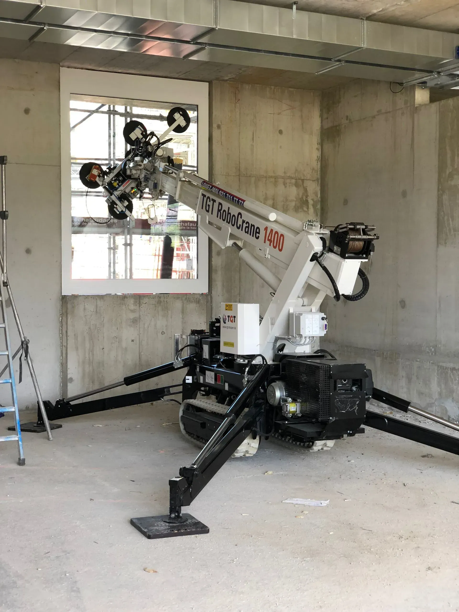 Robot lève-vitre blanc à l'intérieur d'un bâtiment, près d'une fenêtre. Supports noirs déployés.