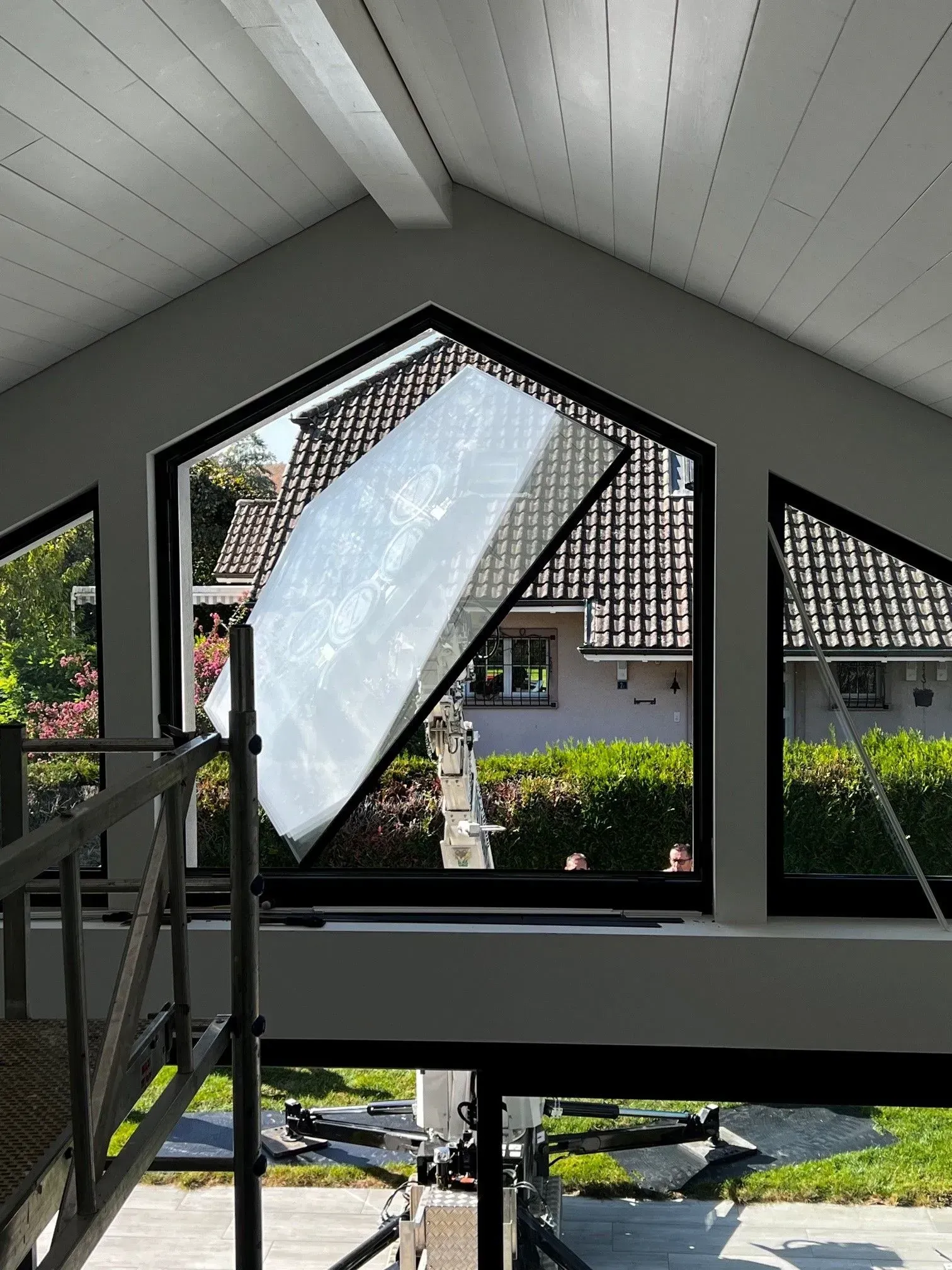 Une grue jaune soulevant une grande boîte emballée contre un ciel bleu avec des nuages.