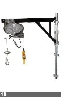 Palan électrique monté sur un bras noir, fixé à un poteau d'échafaudage. Une commande jaune est suspendue.