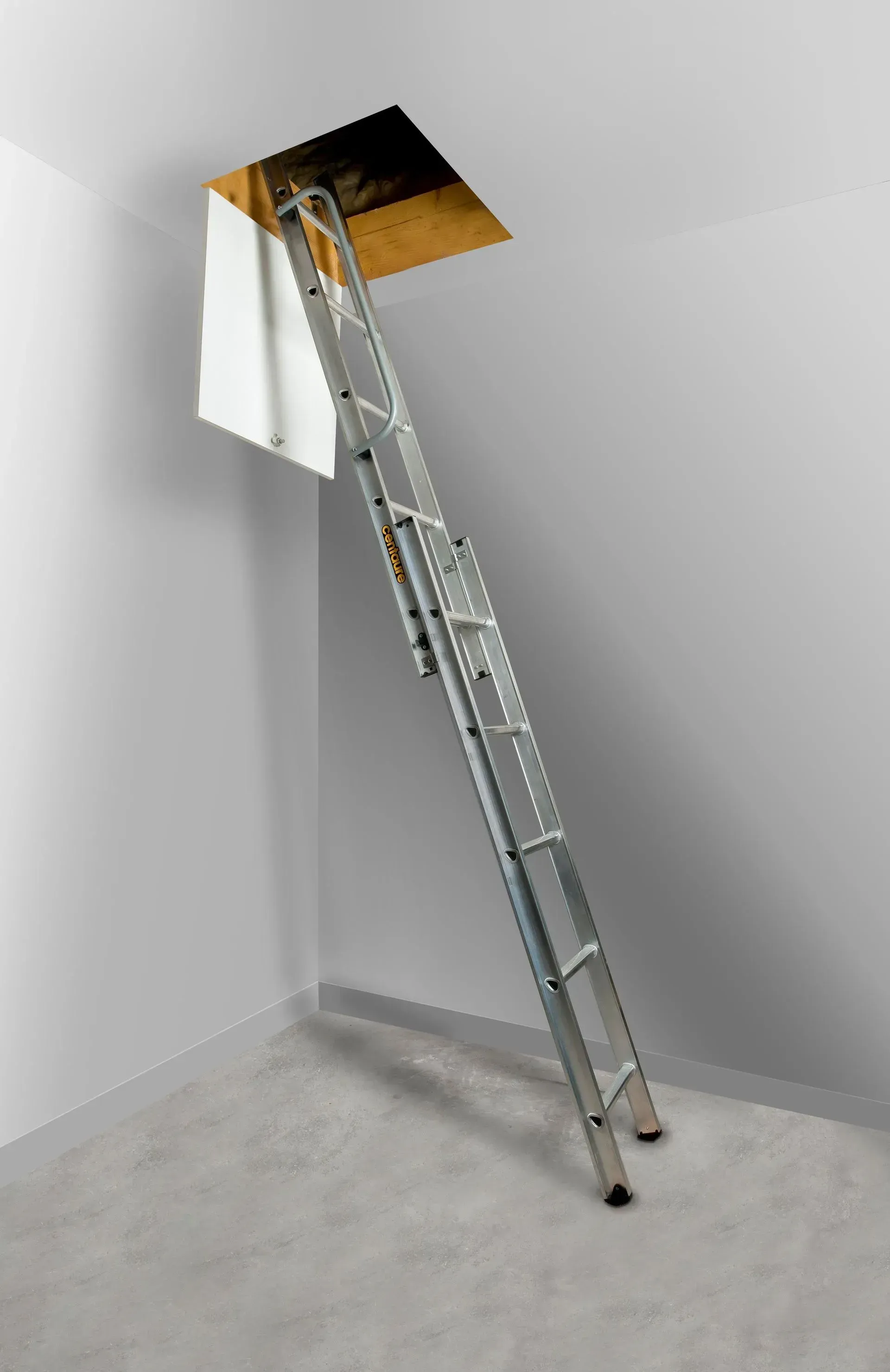 Échelle d'accès au grenier prolongée vers une pièce avec un panneau de porte blanc.