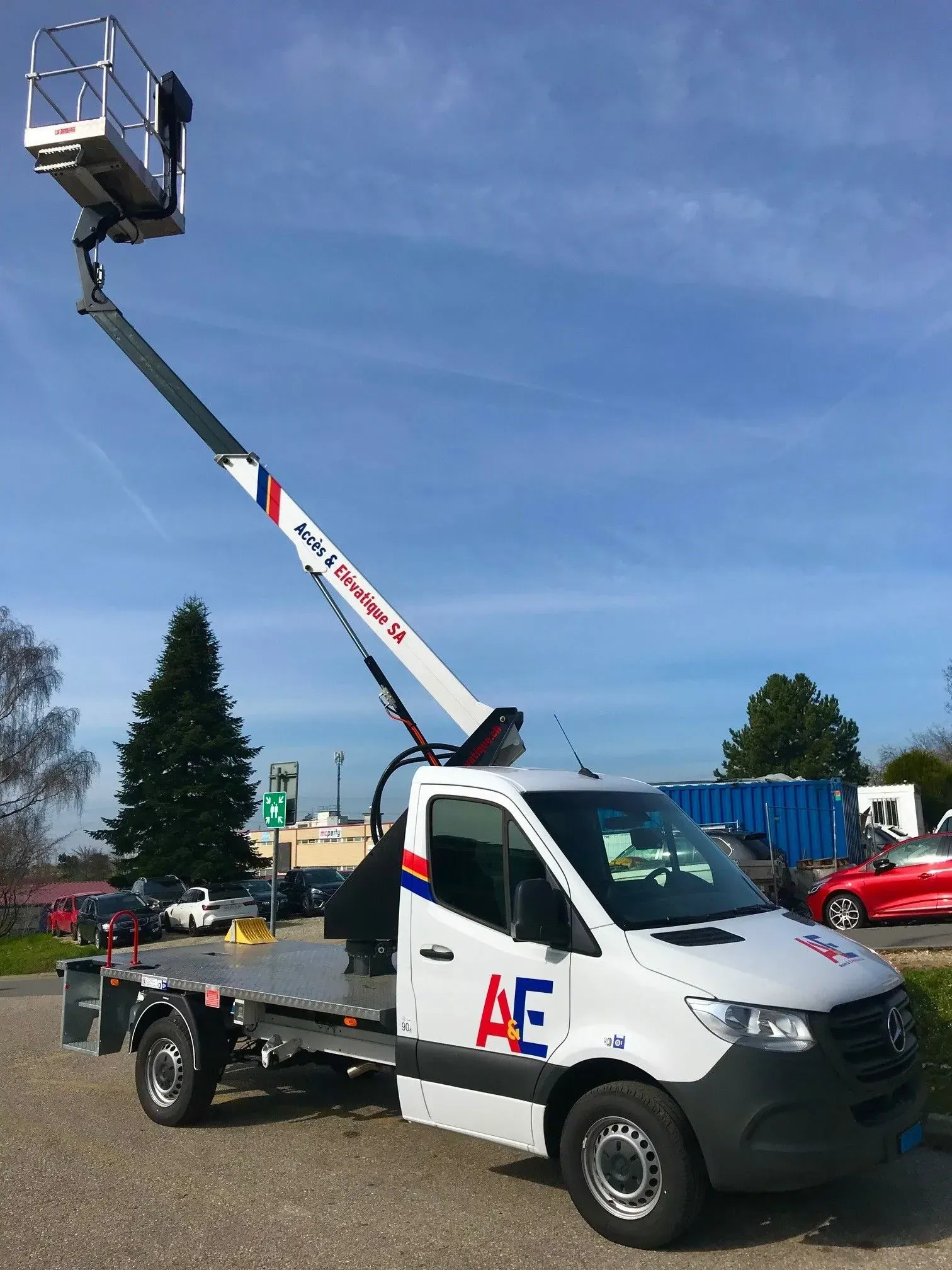 Chariot élévateur blanc avec plate-forme surélevée en extérieur.