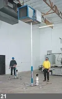 Deux hommes utilisant du matériel dans un atelier, une boîte bleue surélevée sur un grand support.