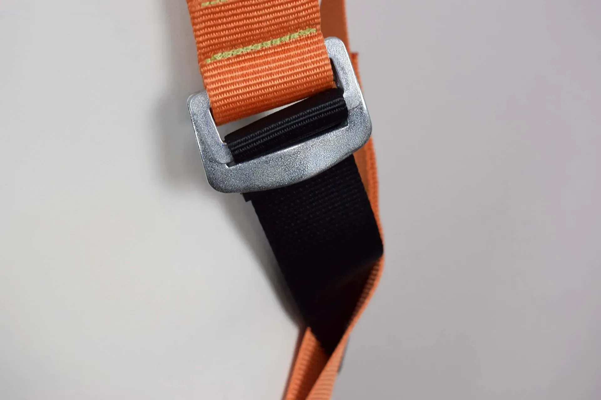 Sangle orange et noire avec une boucle en métal, probablement une ceinture de sécurité.