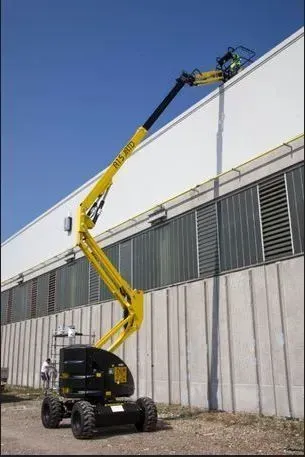 Nacelle articulée jaune s'étendant vers un bâtiment blanc.