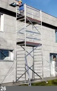 Un ouvrier sur un grand échafaudage à l'extérieur d'un bâtiment, tenant un luminaire.