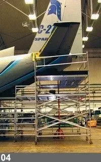 Plateforme d'échafaudage positionnée à côté de la queue d'un avion à l'intérieur d'un hangar.