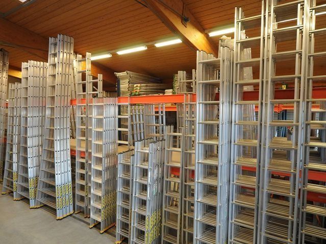 Rangées d'échelles en aluminium stockées dans un entrepôt.