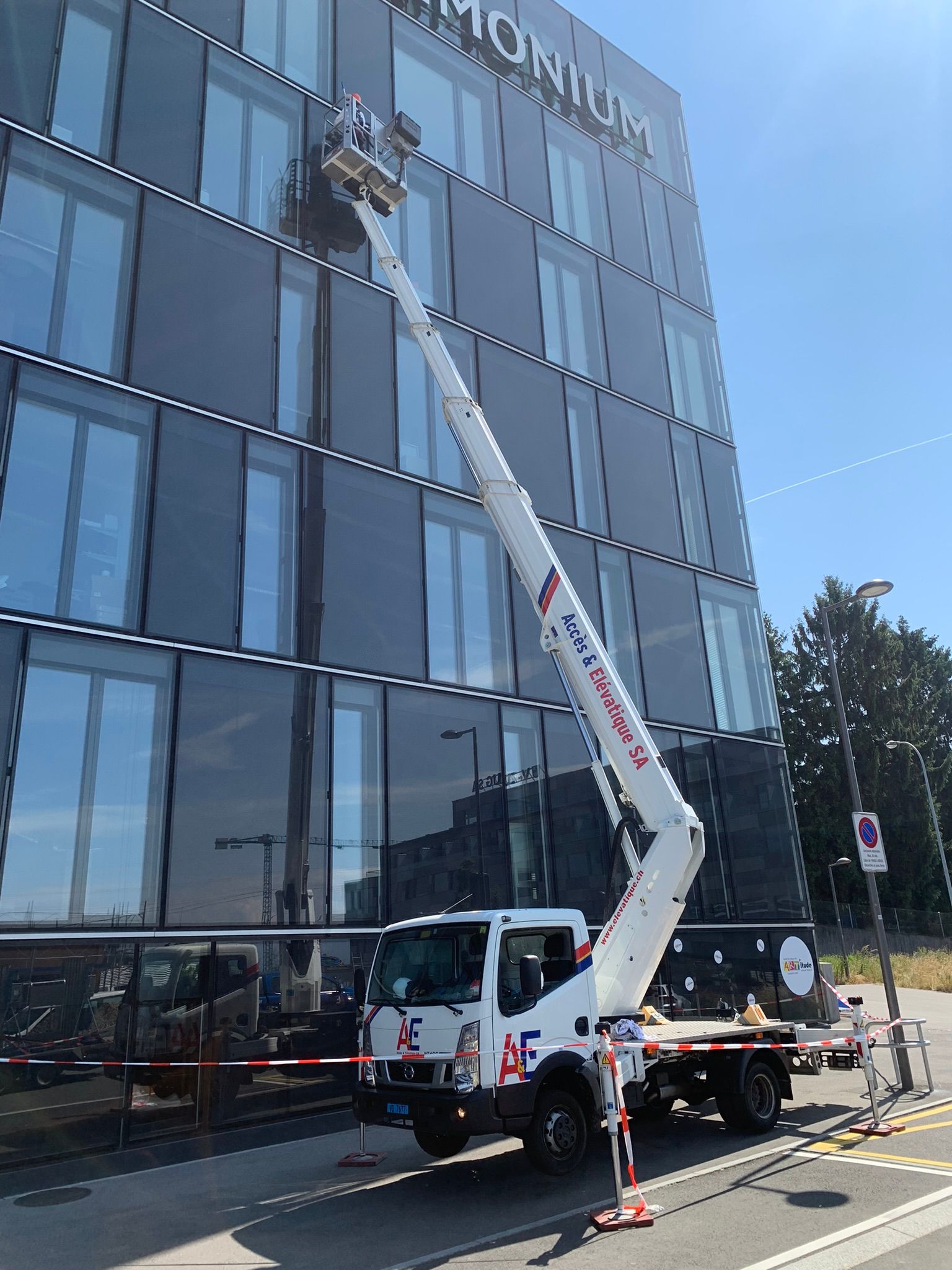 Une nacelle élévatrice atteint les étages supérieurs d'un immeuble de bureaux vitré lors de travaux de maintenance extérieurs