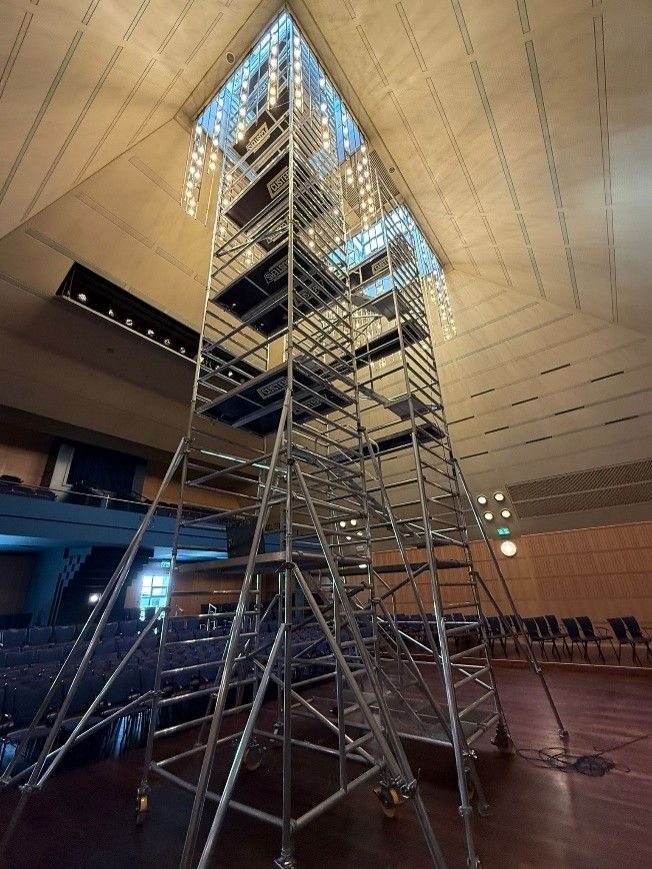 Une haute tour d'échafaudage dans un hall intérieur avec un haut plafond et des rangées de sièges.