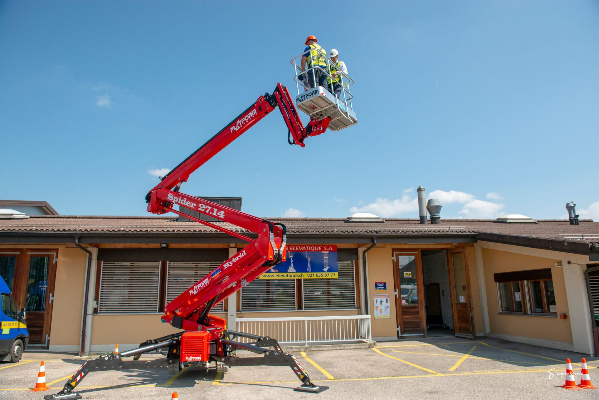 Une femme en équipement de sécurité sur un ascenseur inspecte des panneaux solaires contre un ciel bleu.