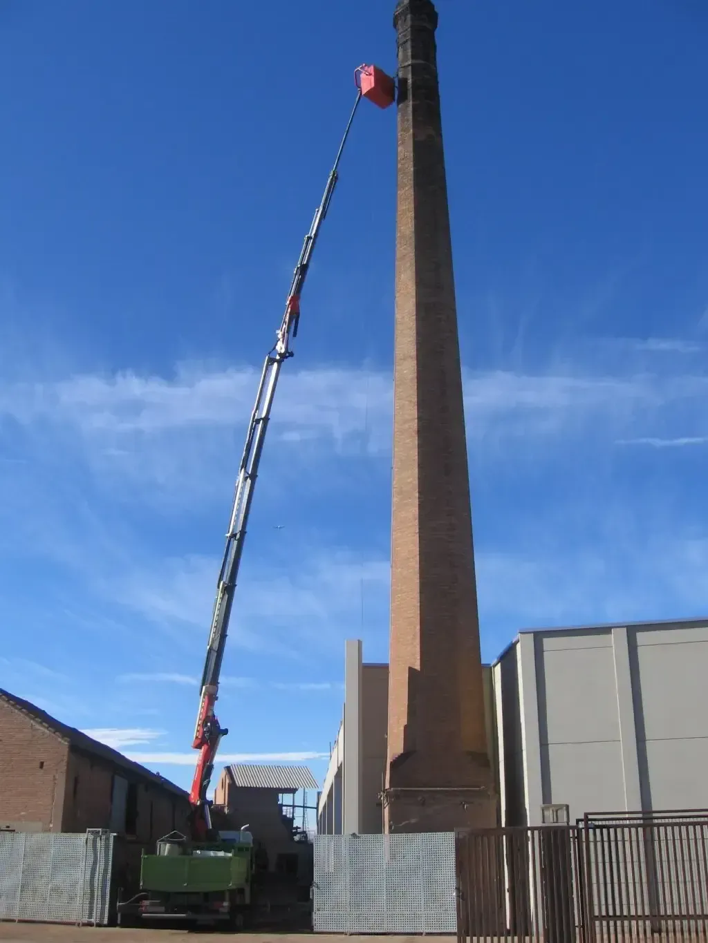 Una gran chimenea de ladrillo con una grúa unida a ella