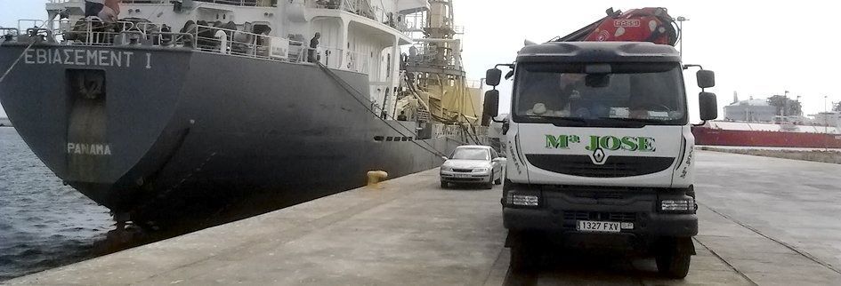 Un gran barco está atracado junto a un camión blanco.