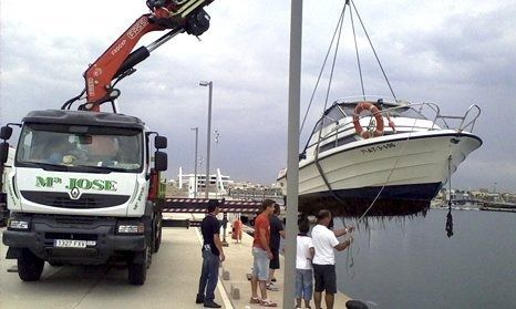 Un camión del señor José está levantando un bote al agua.