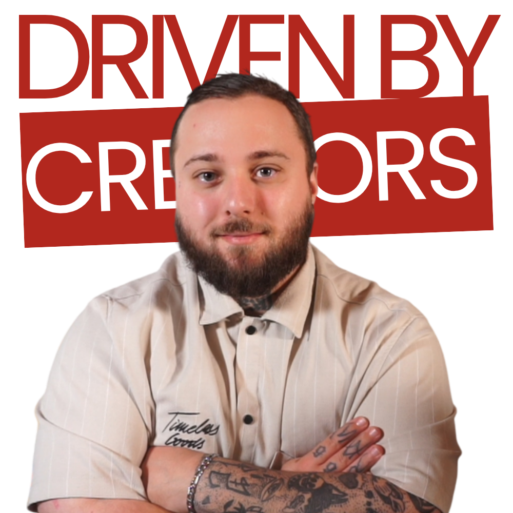 Menschen sitzen um einen Tisch herum und führen unter einer Hängelampe ein Brainstorming mit Laptops und Papier durch.