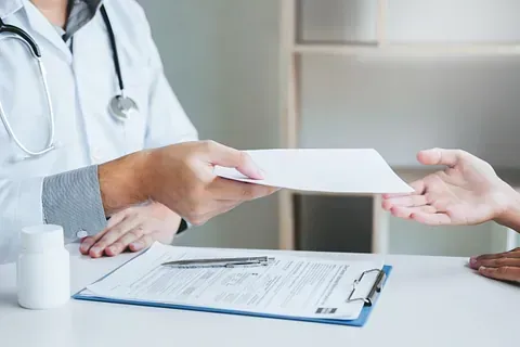 Un médico le entrega un trozo de papel a un paciente.