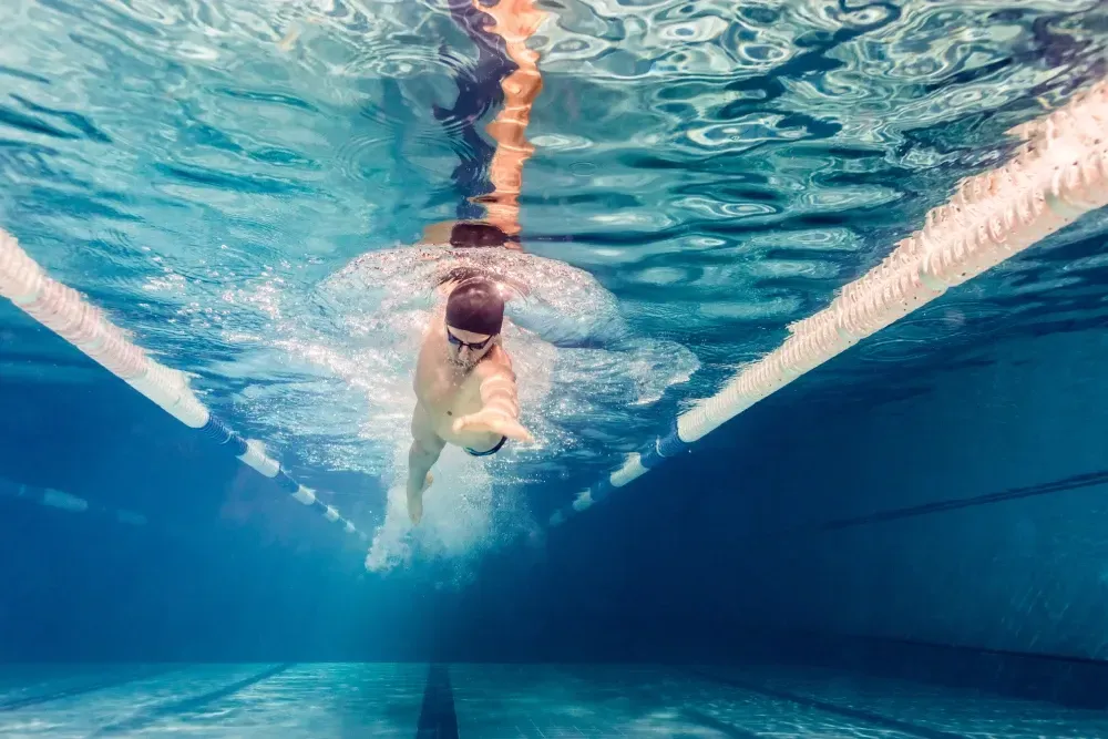 Un hombre está nadando bajo el agua en una piscina.