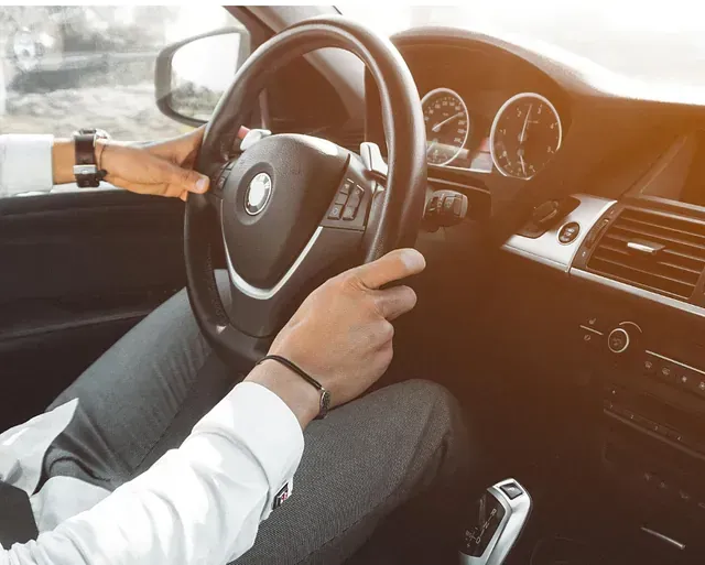 Un hombre conduce un coche con un reloj en la muñeca.