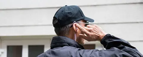 Un hombre que lleva sombrero y gafas de sol está hablando por un teléfono celular.