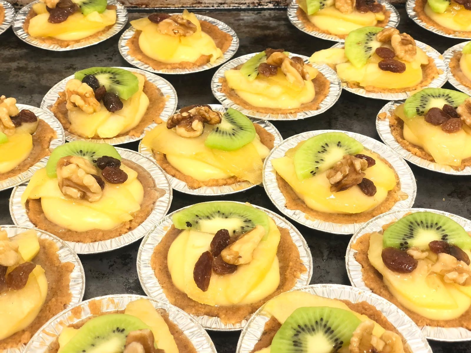 Tartaletas variadas de frutas con kiwi y frutos secos dispuestas en una bandeja