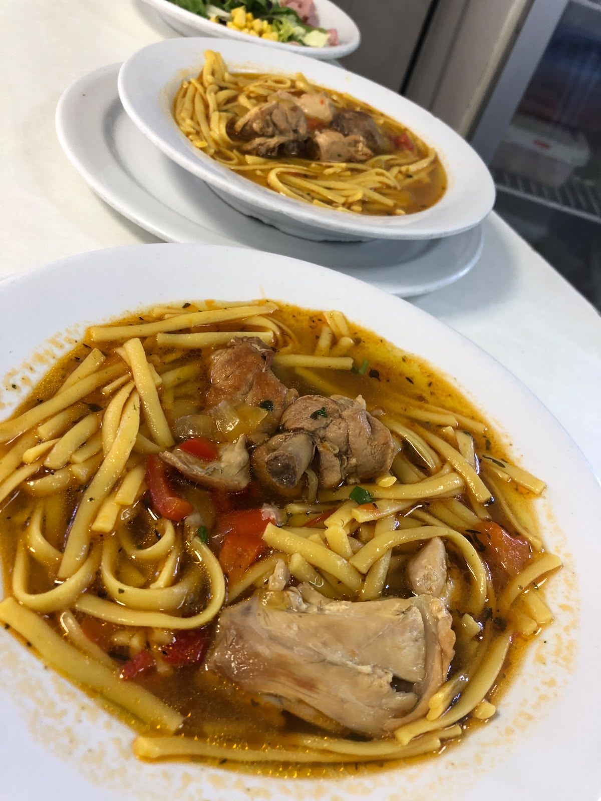 Dos platos de guiso con fideos y carne sobre una mesa, uno en primer plano y el otro al fondo