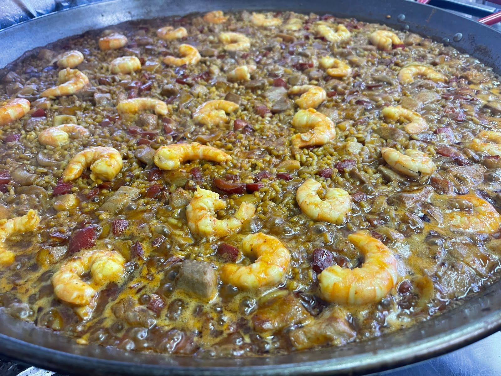 Gran paellera de marisco con gambas y arroz, cocinada en una bandeja metálica poco profunda