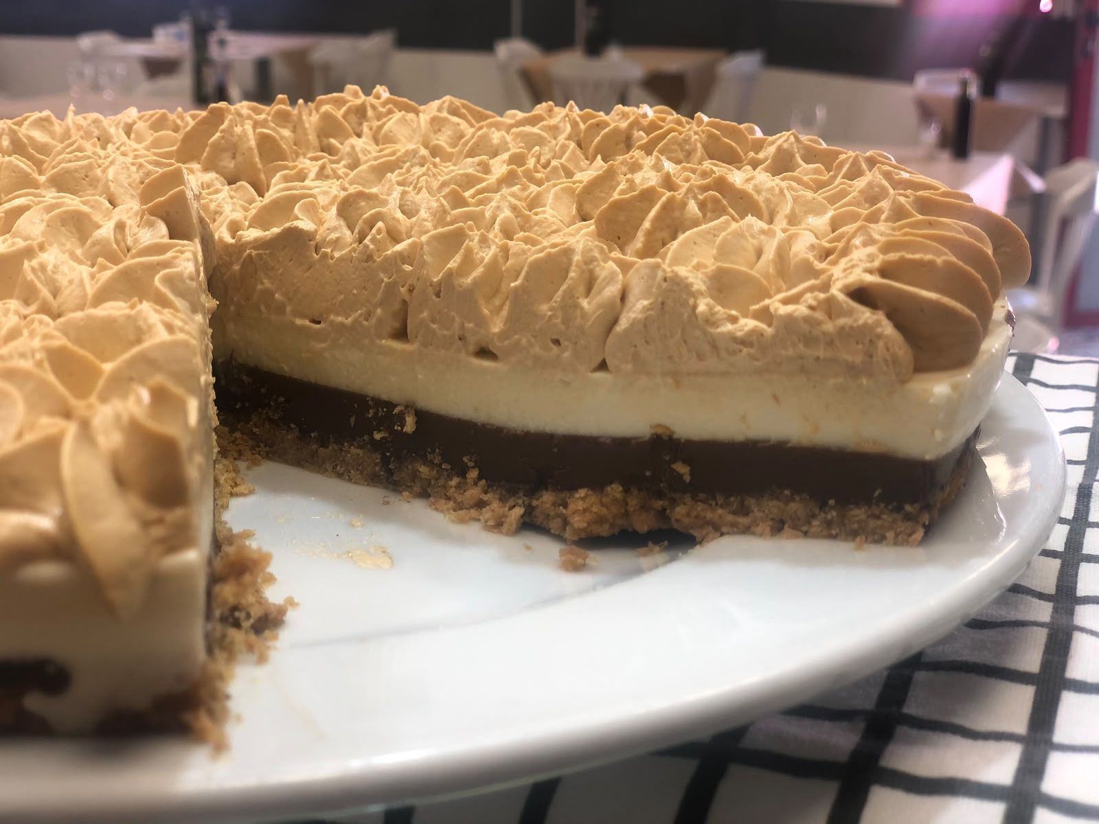 Porciones de tarta de varias capas con crema cubierta de caramelo, servidas en un plato blanco en una cocina