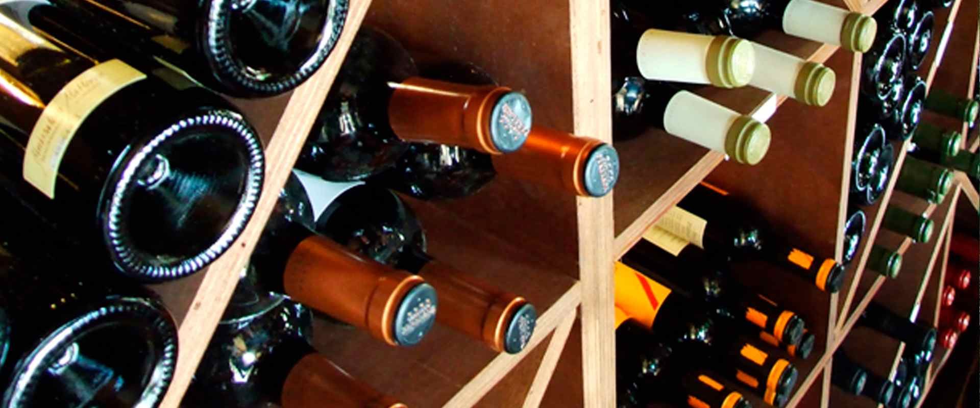 Una fila de botellas de vino apiladas una encima de otra en un estante de madera.
