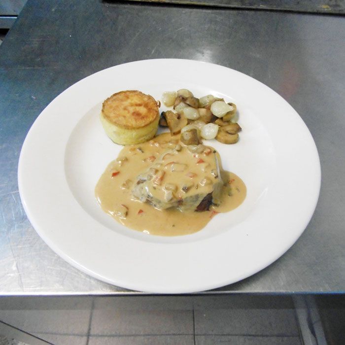 Un plato de comida con salsa y patatas en una mesa.