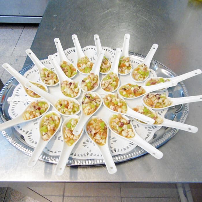 Una bandeja de cucharas llenas de comida sobre una mesa.