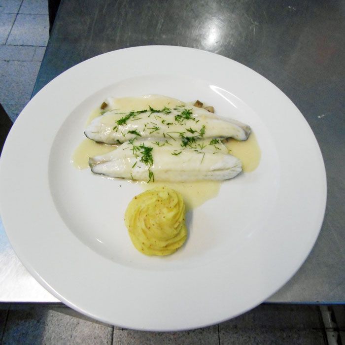 Un plato blanco con pescado y puré de patatas encima.