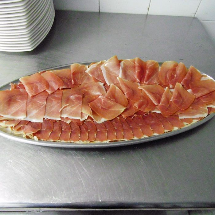 Una bandeja de carne se encuentra sobre un mostrador de acero inoxidable.